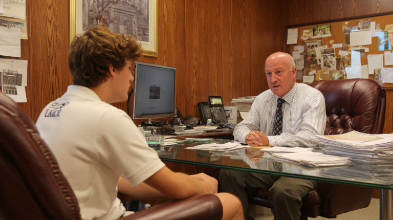 A student is meeting with a counselor in his office.