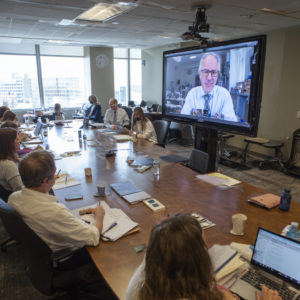 A conference room is meeting a doctor via teleconference.