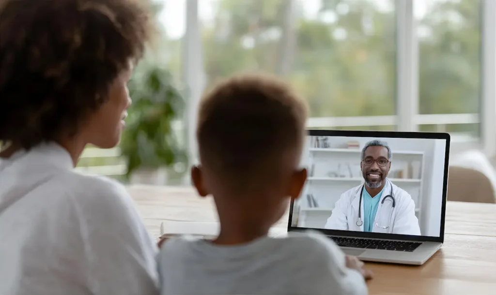 Parent and child in a virtual teletherapy session with dual-licensed providers.